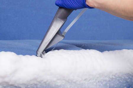 cleaning vacuum cleaner, using a brush, close-up, collects a thick white foam, after removing stains, from textilesの写真素材