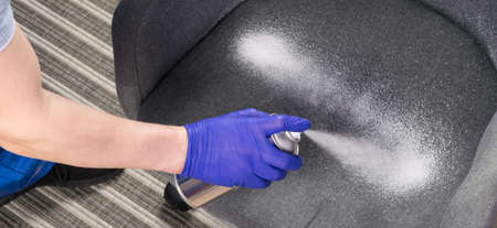 close-up of cleaning a gray chair with a can of white foamの写真素材