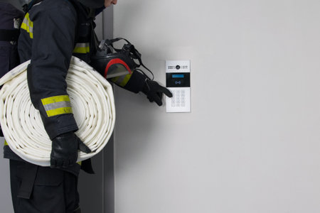 a firefighter in protective clothing, with fire extinguishing equipment, tries to open a closed door by dialing the intercom code, there is a place for the inscriptionの写真素材