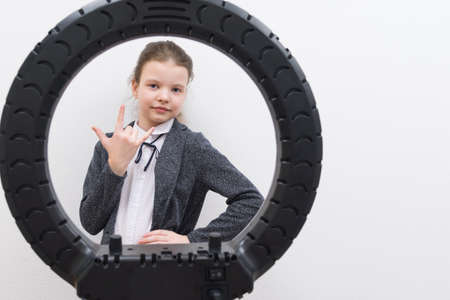 a girl in a gray jacket, in the center of a circular lamp, shows three fingers, there is a place for the inscriptionの写真素材