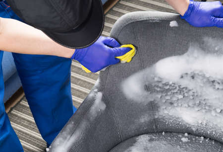 close-up of cleaning a gray chair with thick white foam and a rag, by handの写真素材