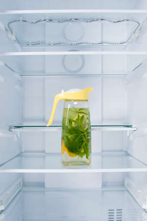 lemonade in a jug of citrus and mint, in the refrigerator, on a glass shelf, on a white backgroundの写真素材