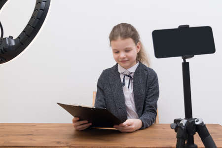 a girl conducts a video broadcast, surrounded by a smartphone and a circular lampの写真素材