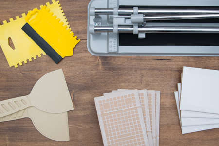 on a wooden background, tools for building and laying interior tiles, spatulas and a cutterの写真素材