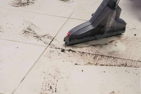 the brush of the washing vacuum cleaner removes the marks of the sole of the shoes on the floor of the ceramic tilesの写真素材