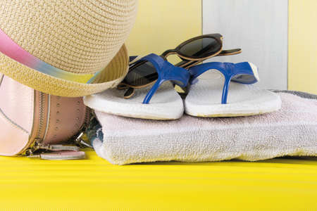 towel, flip flops and hat on yellow suitcase: beach holiday conceptの写真素材