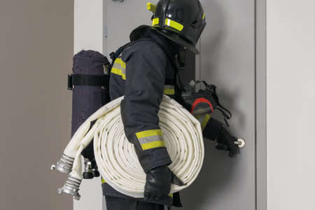 a firefighter with a hose line in his hands looks out the window of a closed doorの写真素材