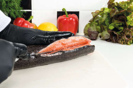 the hand of the chef cut fresh trout into fillet, close-up, front viewの写真素材