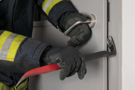 the fireman's hands open the closed door with a special toolの写真素材
