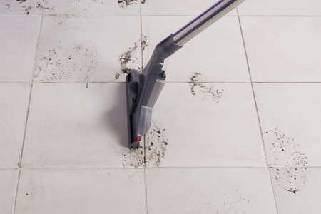light tile with dirty spots, cleaning with a washing vacuum cleaner, close-up, side viewの写真素材