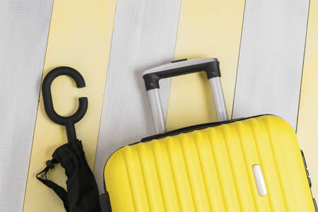 umbrella and yellow travel suitcase on gray-yellow backgroundの写真素材