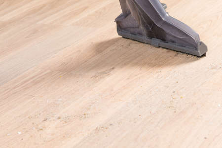 the brush of a washing vacuum cleaner cleans the laminate flooring, close-up, side viewの写真素材