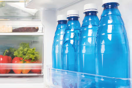drinking water in bottles on the shelf in the refrigerator door, side view, close-upの写真素材