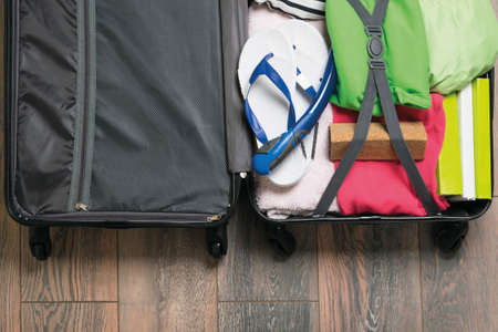 open suitcase with beach holiday items on dark wooden floor backgroundの写真素材