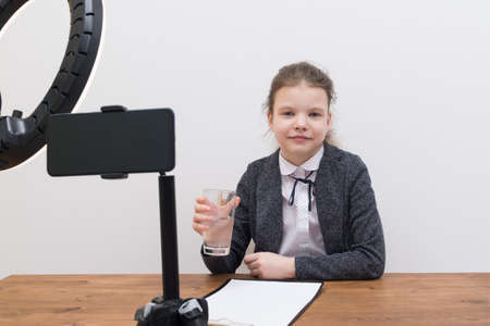 girl blogger, takes a break, during a video broadcast, drinks waterの写真素材