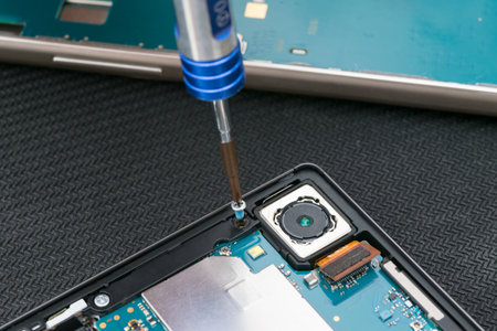 close-up of a screwdriver unscrewing a screw from a mobile phone caseの写真素材