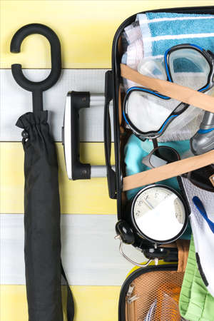 on a gray-yellow background, an open suitcase for traveling and a set of items for relaxing in it, a...