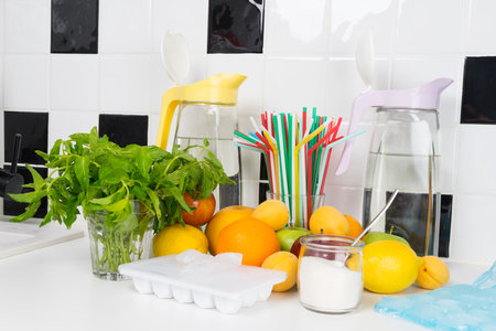 against the background of a black and white kitchen, a set of products for making a refreshing drink, fruit, mint, sugar, ice, tubesの写真素材