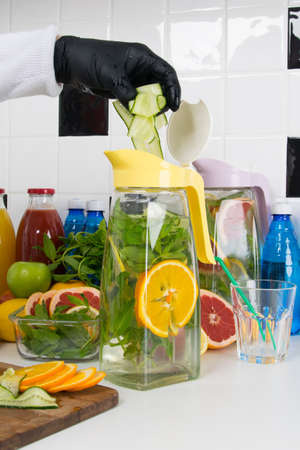 the chef's hands in black gloves are slicing fresh fruits and vegetables to prepare a refreshing summer drinkの写真素材