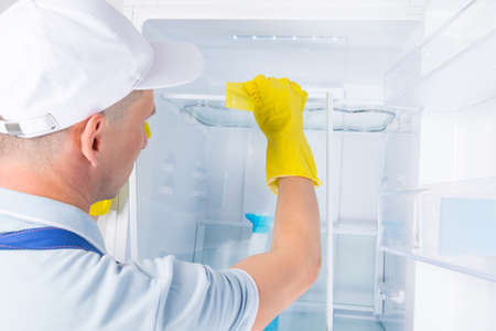 a man in protective clothing disinfects a refrigerator and glass shelvesの写真素材