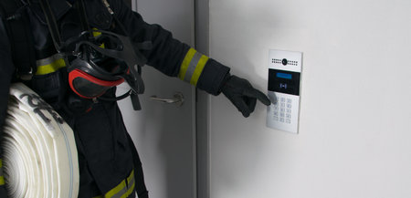 a firefighter in protective clothing, with fire extinguishing equipment, tries to open a closed door by dialing the intercom code, close-upの写真素材