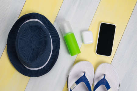 on the gray-yellow surface, beach flip-flops, a hat and mobile gadgets, a phone and wireless headphones in a caseの写真素材