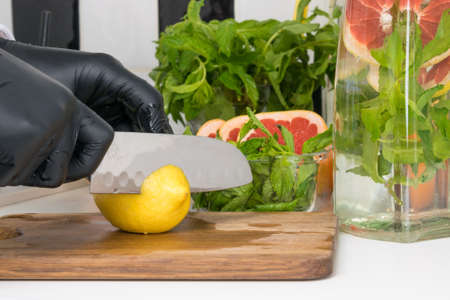 the chef slices a lemon with a knife for fruit drinksの写真素材