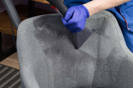 the brush of the washing vacuum cleaner collects moisture from the upholstery of the chairの写真素材