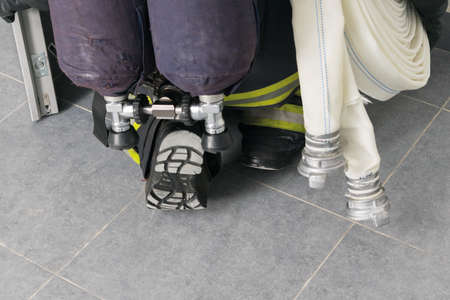 a firefighter with equipment crawls through an open door to extinguish a fire in a building, close-upの写真素材