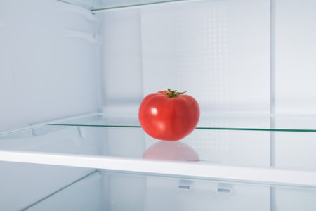 red tomato on a glass shelf in the refrigeratorの写真素材