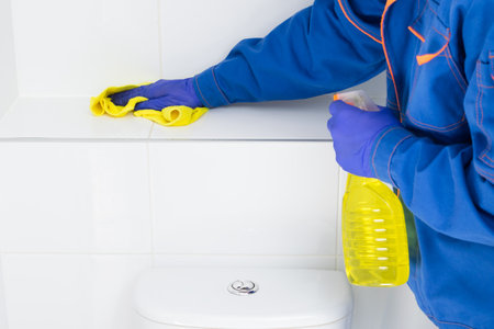 an employee of the cleaning company wipes the tiles in the bathroom using special productsの写真素材