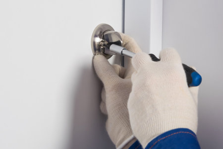 foreman's hands repairing a lock on a white front door, close-upの写真素材