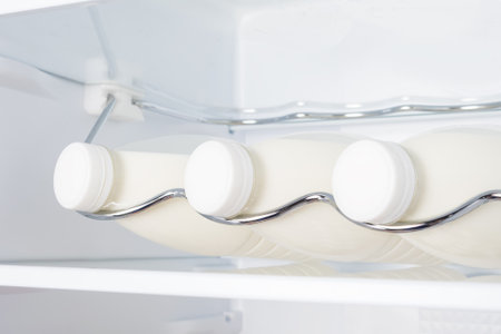 three bottles of farm milk on a shelf in the refrigerator, close-upの写真素材