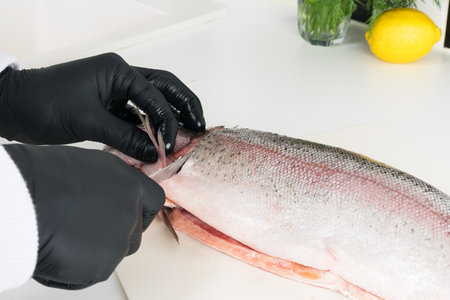 the hands of the chef are busy cooking red fish, close-upの写真素材