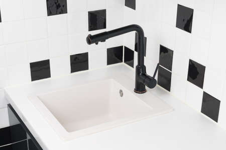 against the background of a black and white kitchen, a sink and a faucetの写真素材