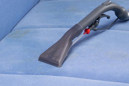 close-up of a washing vacuum cleaner on a blue dirty sofaの写真素材