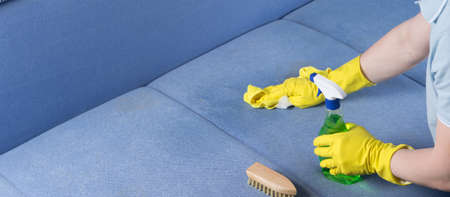 specialist in protective gloves, cleans the soiled surface of the sofa with foam, a brush and a clothの写真素材