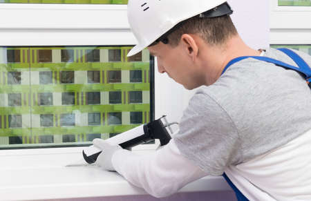 the worker seals the seams of the windows in the roomの写真素材