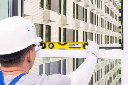 a man in a helmet checks the level of the windows after installing themの写真素材