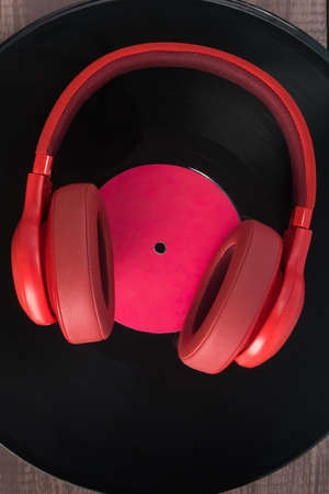 red headphones lie on an old vinyl record, top viewの写真素材