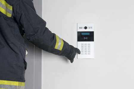 the fireman's hand dials the code of the electronic intercom to open the iron door