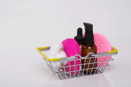 on a white background, in an iron basket, there are massage oil and sponges for cleaning the faceの写真素材