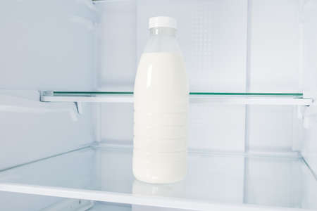 a bottle of milk on a shelf in an empty refrigeratorの写真素材