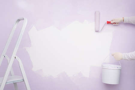 hands with a bucket of paint made an empty white advertising space on the wallの写真素材
