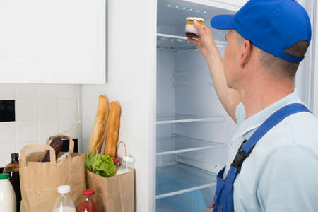 a grocery delivery worker puts them in the refrigeratorの写真素材