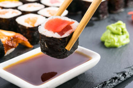 Chinese chopsticks hold a roll in front of the soy sauceの写真素材