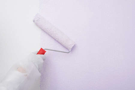 hand in a glove paints over a white wall, close-upの写真素材