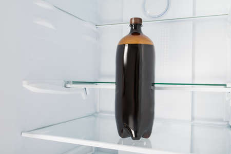 a large plastic bottle of beer stands on a shelf in an empty refrigeratorの写真素材