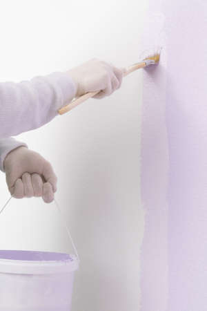 hands in gloves paint the white wall purpleの写真素材