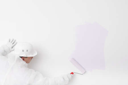 a man in a white helmet paints the wall purpleの写真素材